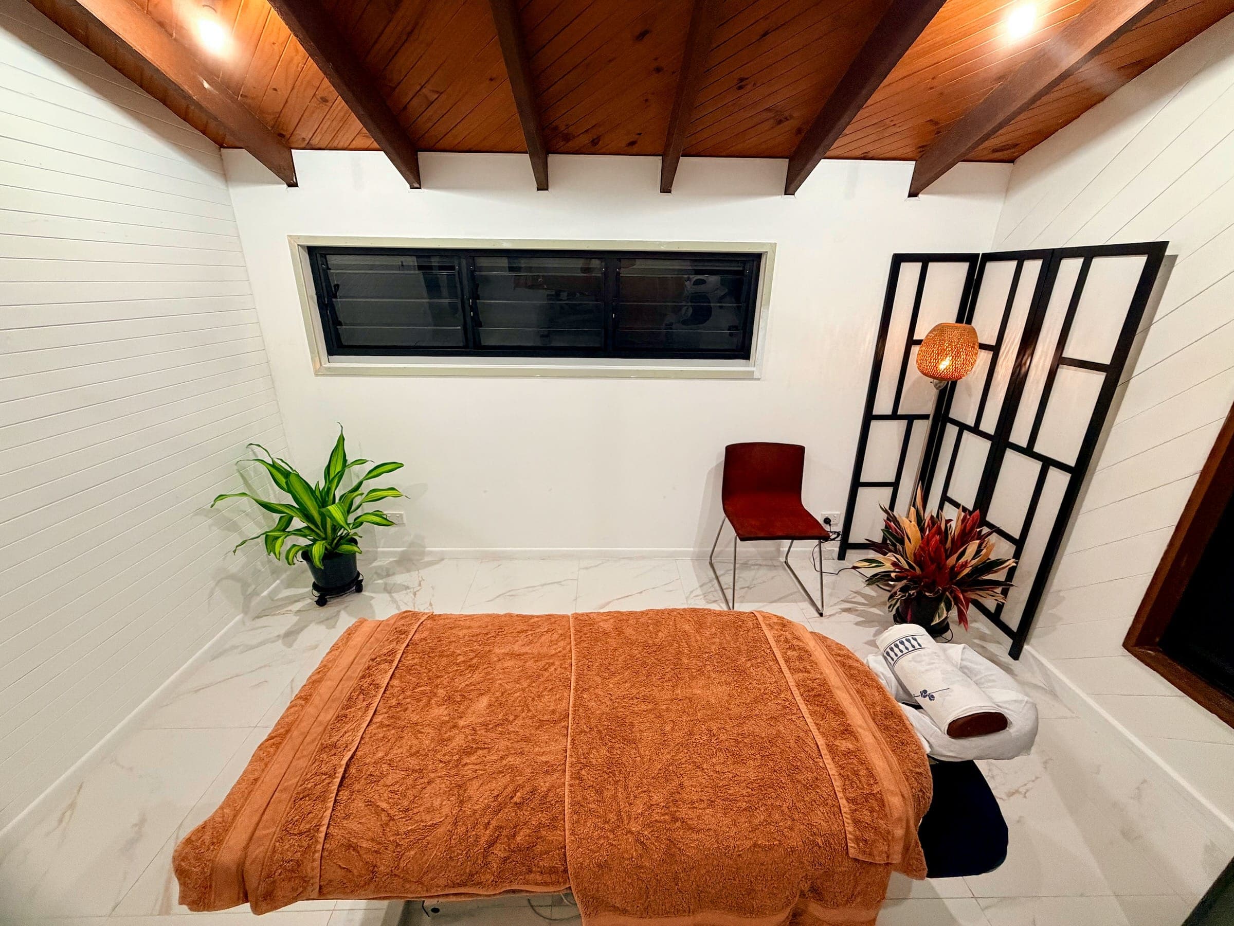 Overhead view of the treatment room at Hideshi Acupuncture in Kewarra Beach, Cairns, with marble floor tiles, treatment table and tropical plants